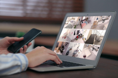 Woman monitoring modern cctv cameras on laptop indoors, closeup. Home security system